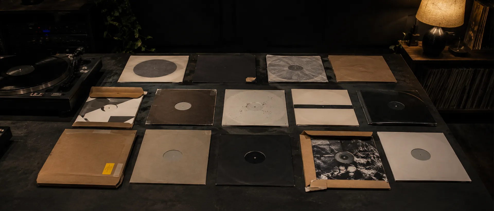 Fourteen records in plain sleeves laid out on the studio table